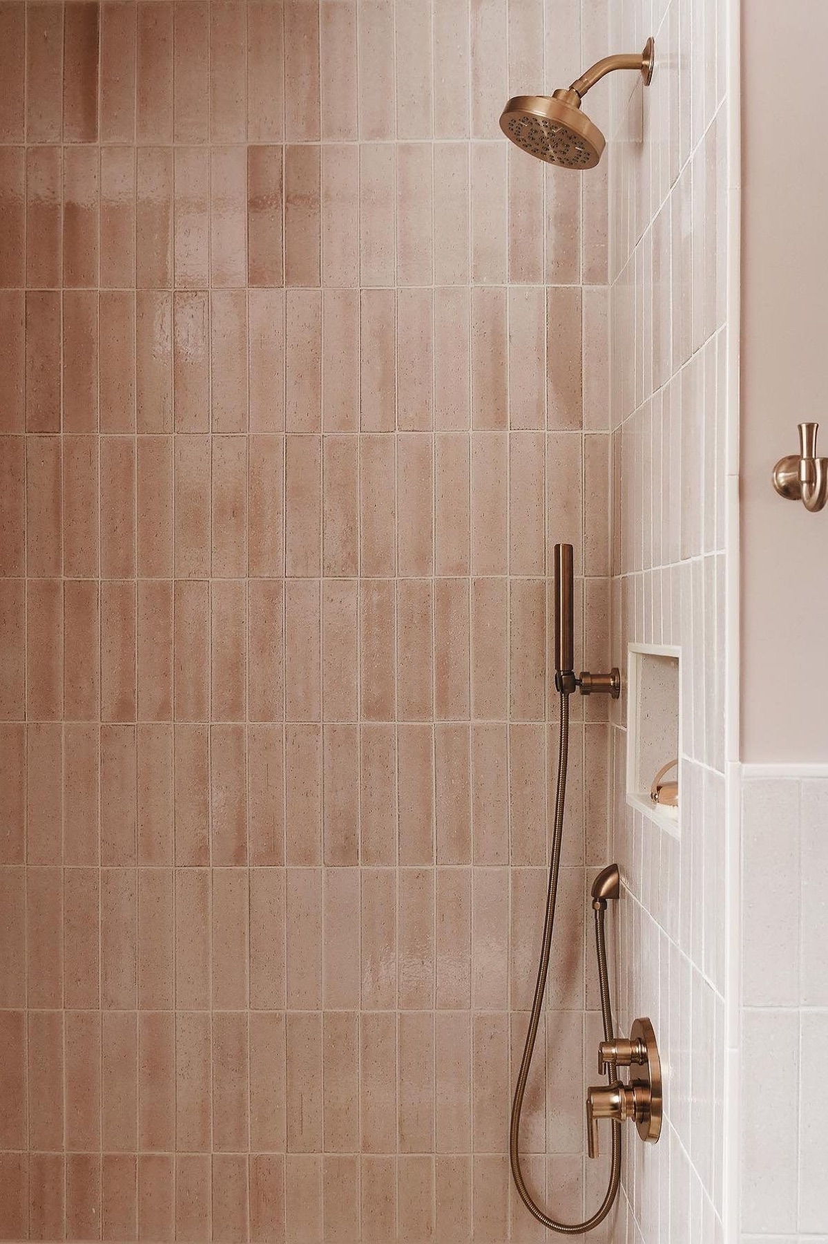 Douche met roze staande tegels en koperen kranen
